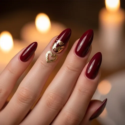 Burgundy almond nails with gold foil heart, blurred romantic background, valentines nails.